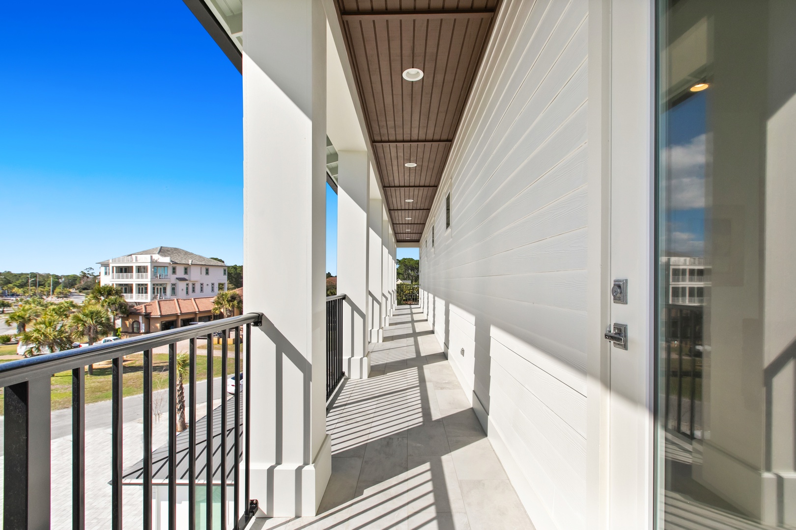 A covered walkway stretches along the second-floor balcony, offering a peaceful spot to take in the surrounding neighborhood and natural light filtering through elegant architectural details.