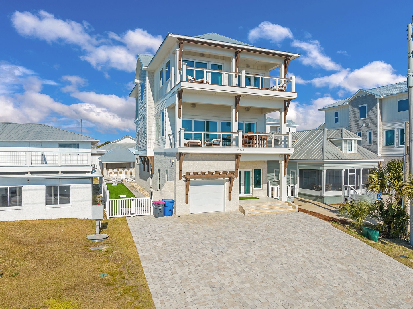 Modern three-story coastal home features multiple balconies and panoramic windows in a peaceful residential neighborhood.