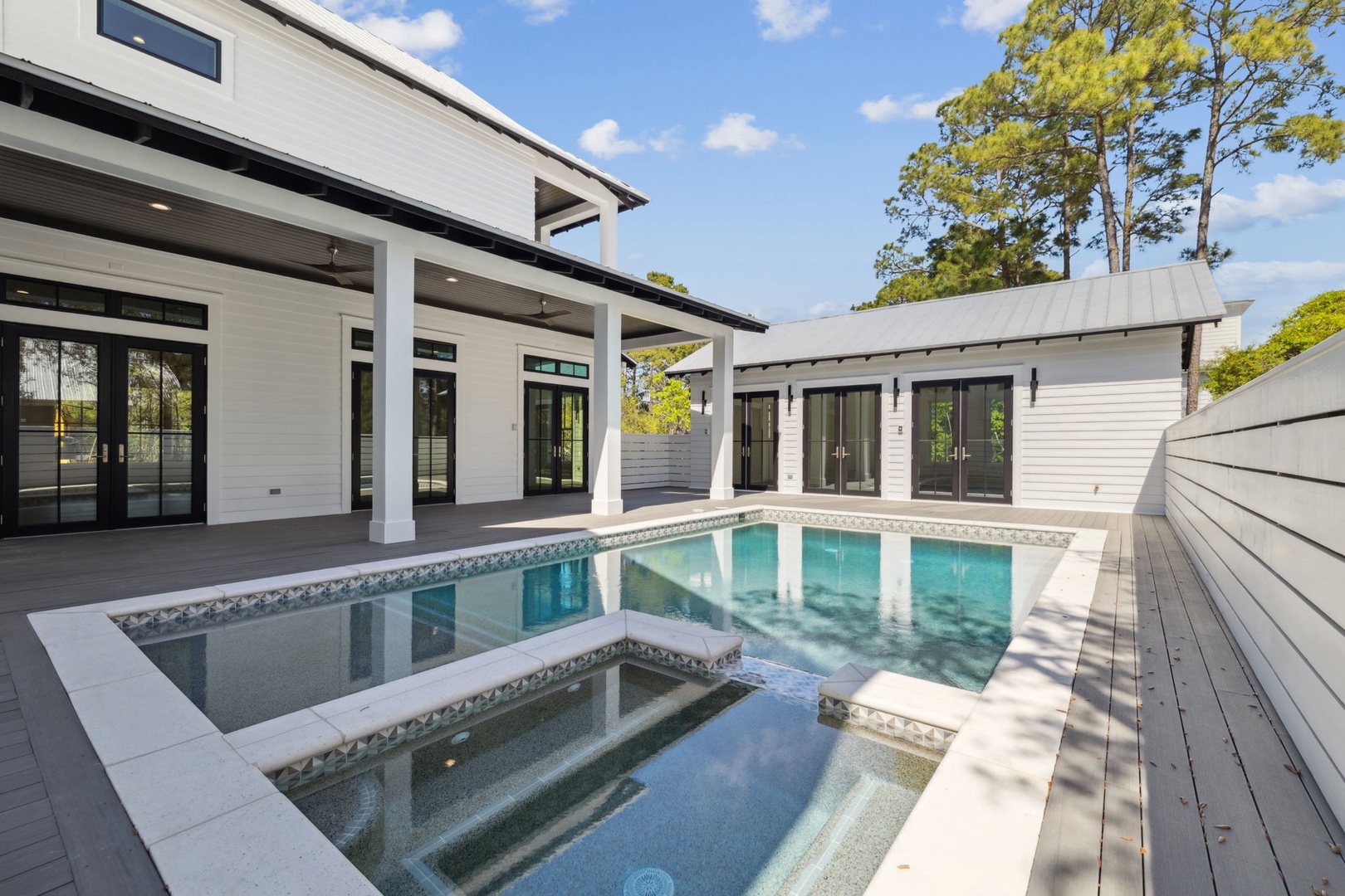 Modern luxury home with pristine pool and spa surrounded by mature trees in a private setting.