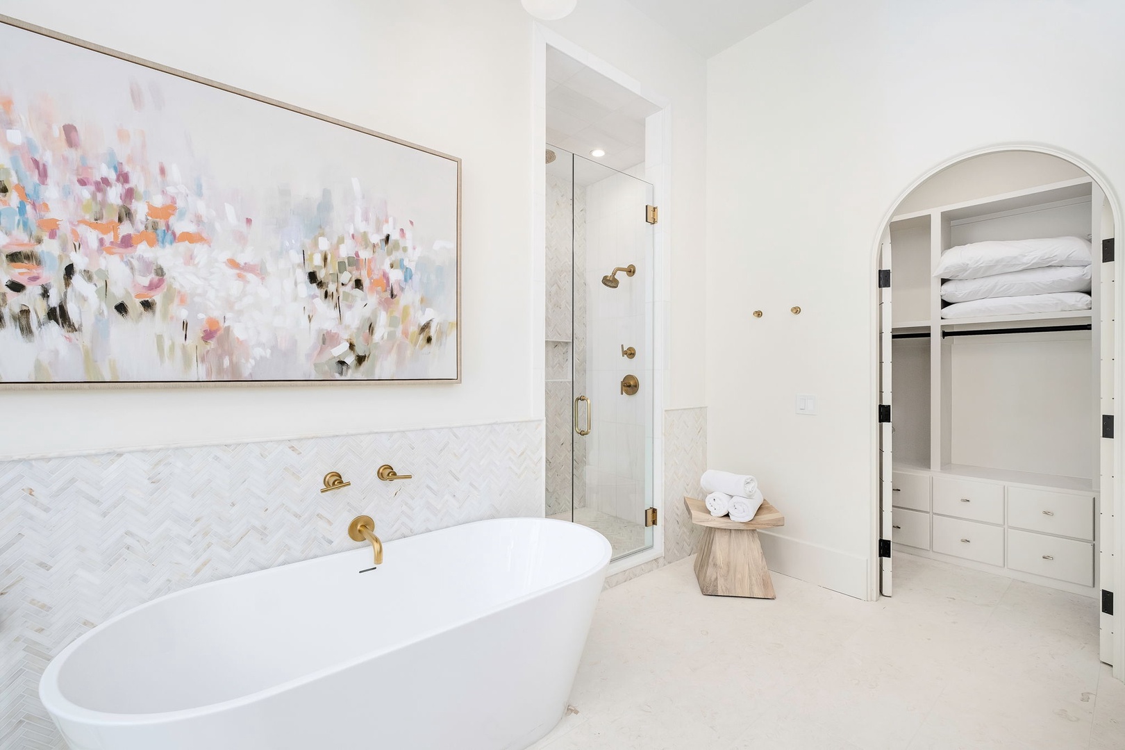 Indulge in a spa-like retreat with a luxurious soaking tub, elegant herringbone marble, gold fixtures, and a spacious walk-in shower—your personal sanctuary awaits.