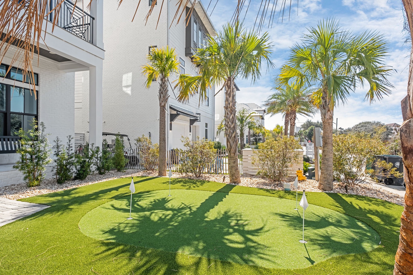 Modern residential community featuring a custom putting green surrounded by palm trees and contemporary architecture.