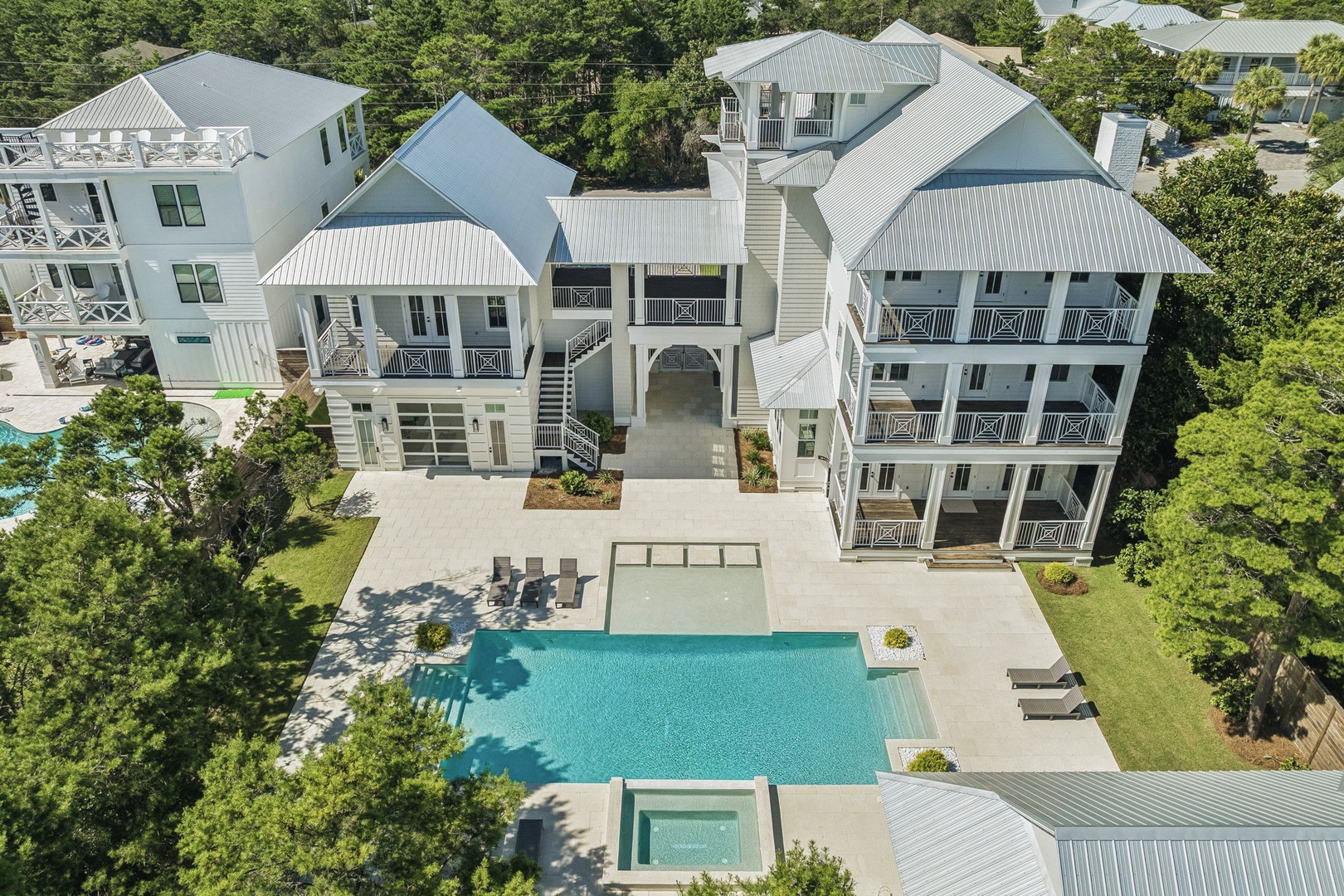 An impressive coastal retreat surrounded by lush greenery, featuring a private pool and multiple balconies that define this spacious property in a quiet residential setting.