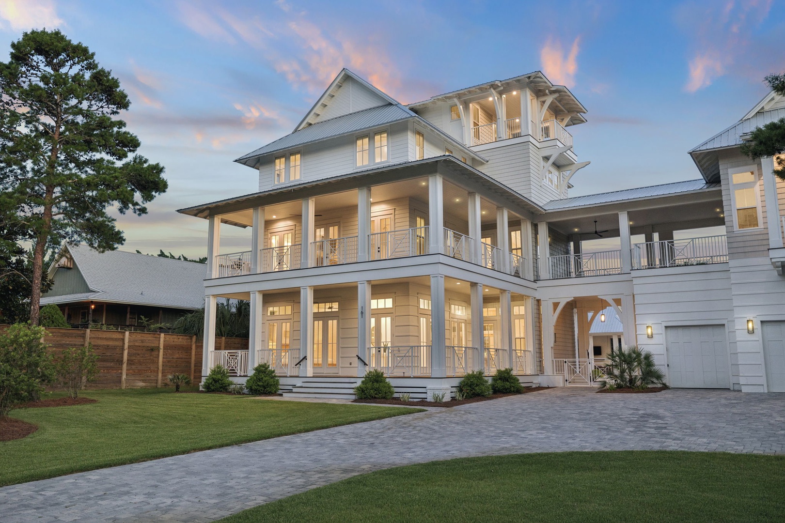 A striking coastal-style property at dusk, where manicured lawns meet elegant architecture and sweeping porches hint at relaxed Southern evenings.