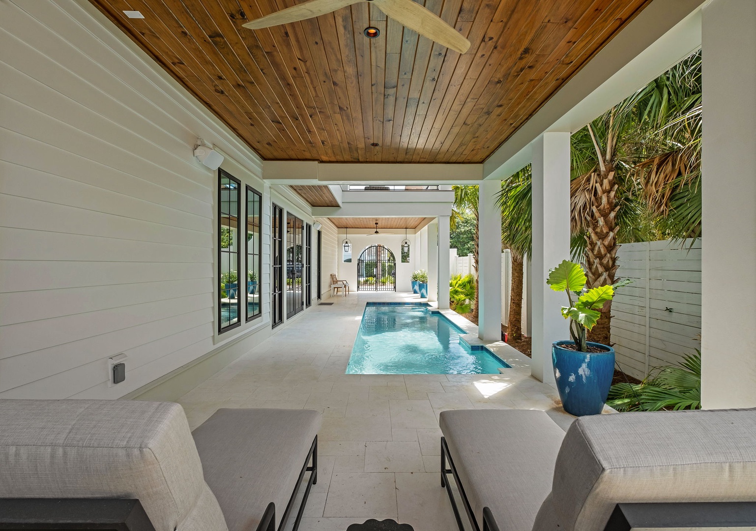Your private covered pool terrace invites relaxation with tropical plants and elegant ceiling fans creating the perfect indoor-outdoor oasis.