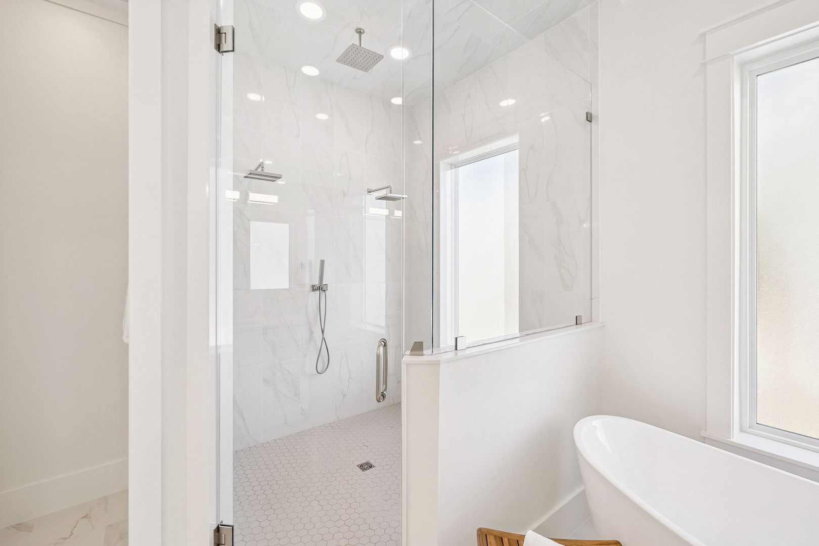 Indulge in your private spa-like bathroom featuring a luxurious soaking tub and rainfall shower with elegant marble finishes.
