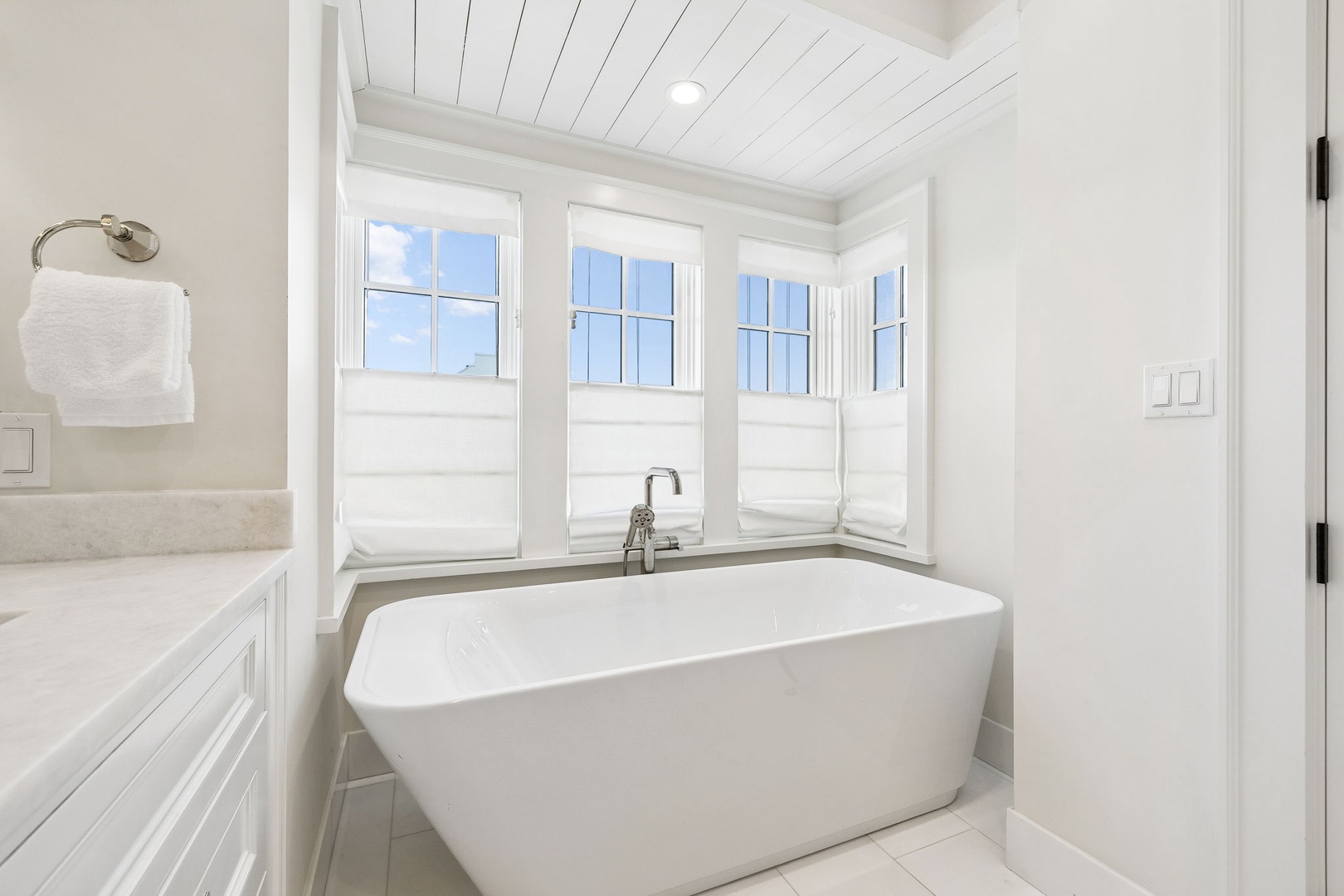 Slip into this elegant freestanding tub and let the soft natural light wash over you. The serene white palette and charming shiplap ceiling create your personal spa retreat.