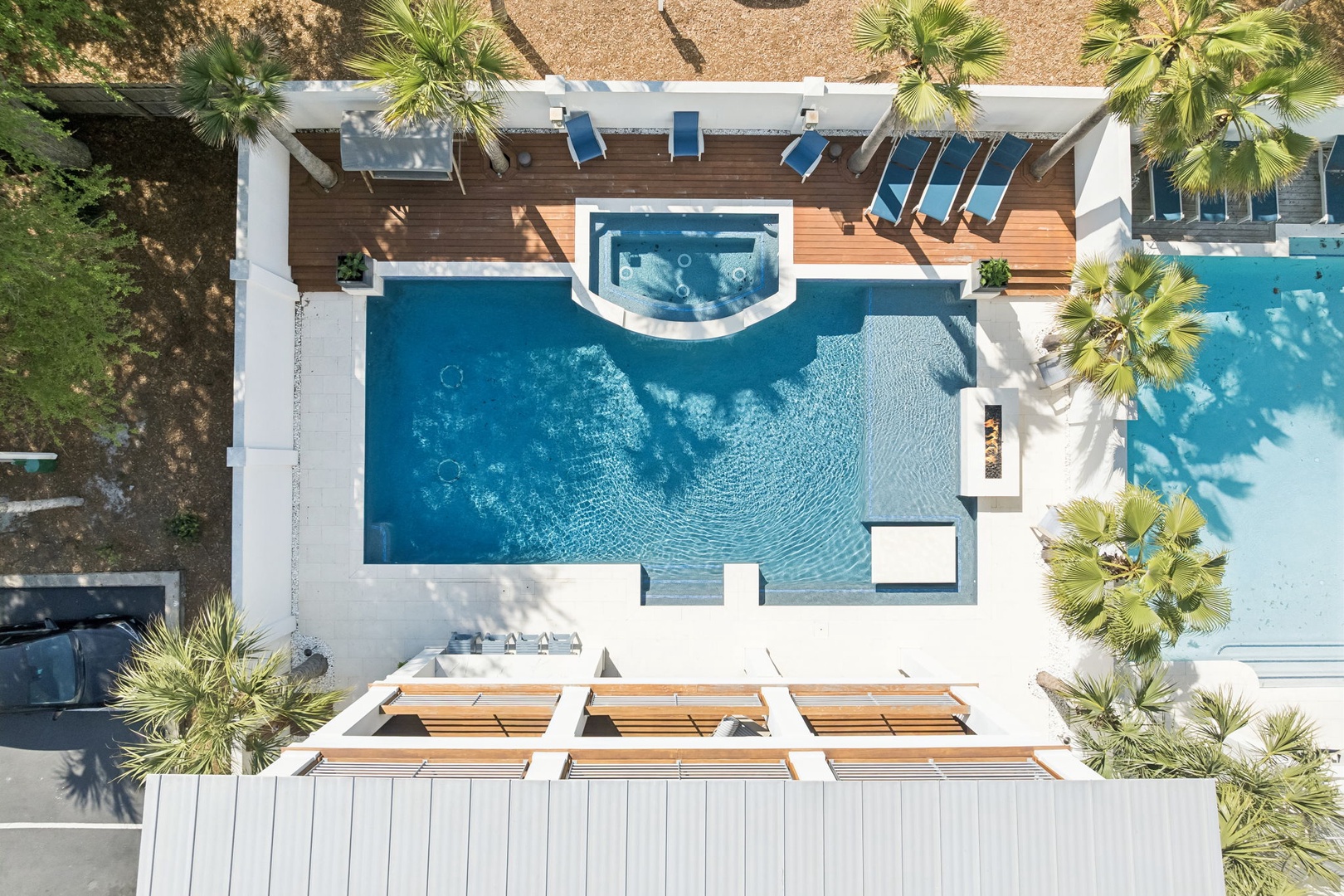 Luxurious aerial view showcasing a pristine pool area with tropical landscaping and elegant outdoor furnishings.