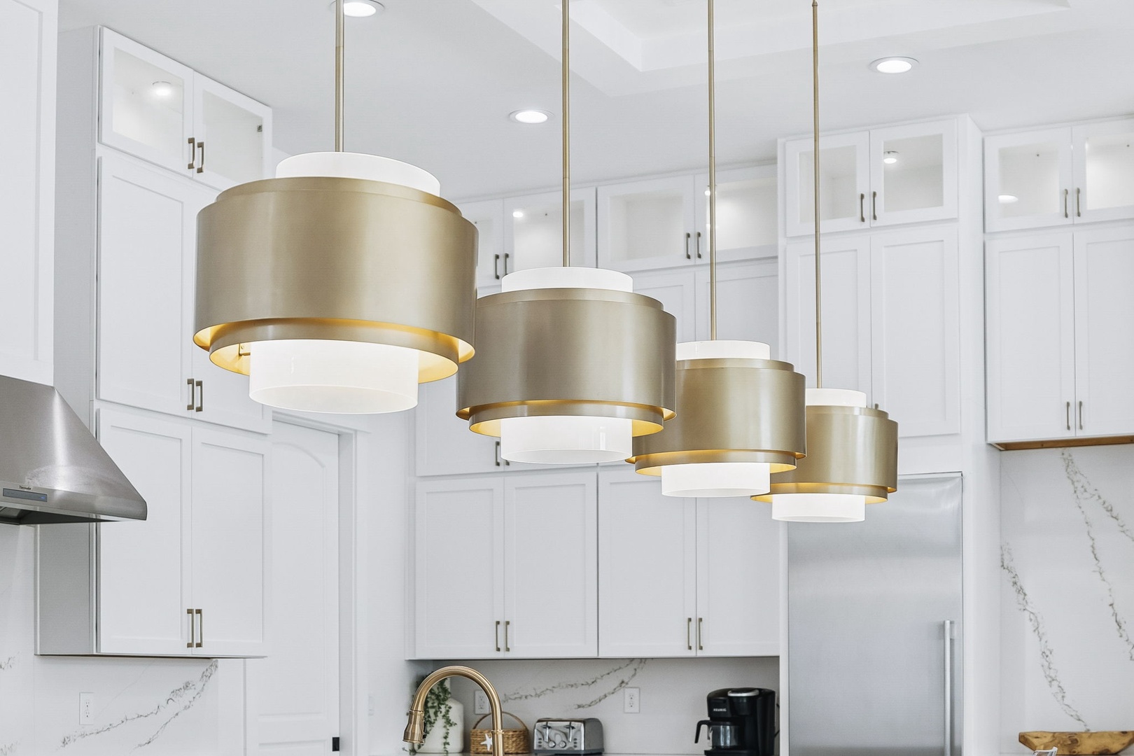 Step into a bright, modern kitchen where elegant pendant lights and sleek marble backsplash create a space that feels both luxurious and inviting.