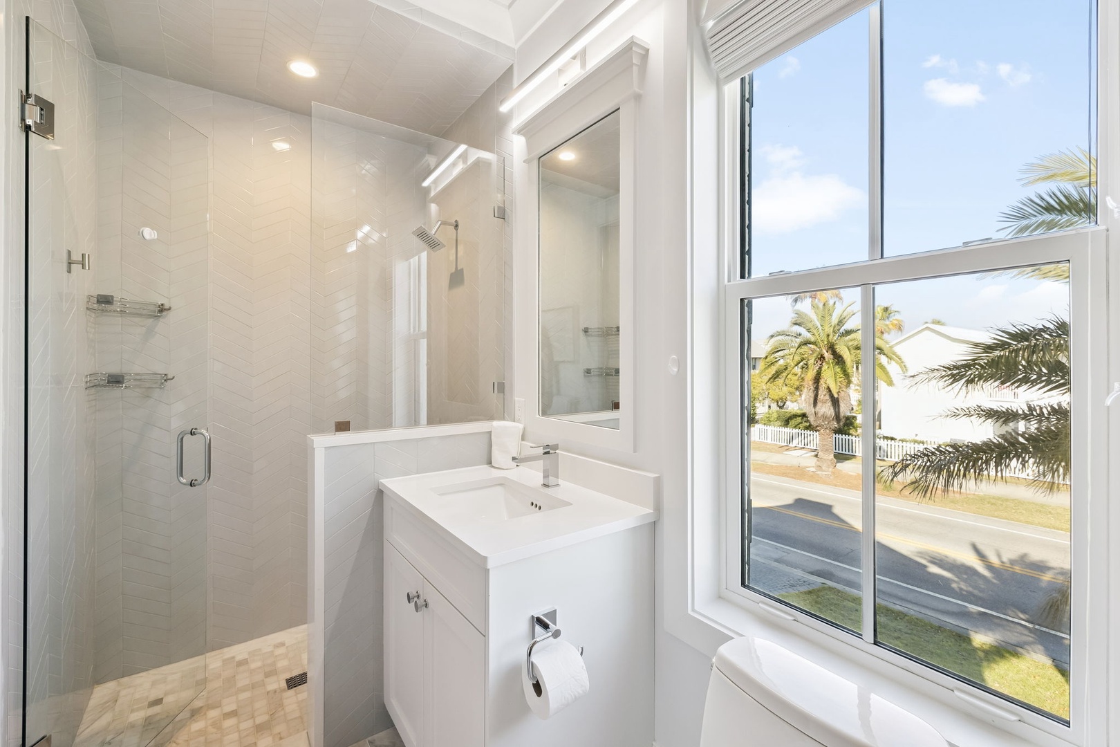 Start your mornings in this bright bathroom where tropical palm views create a serene backdrop for your daily routine.