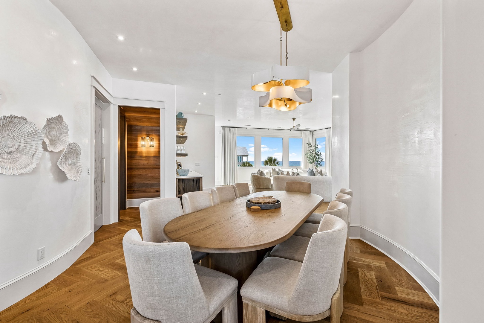Gather around this stunning oval table where shared meals become cherished memories, with natural light and ocean breezes flowing through open windows.