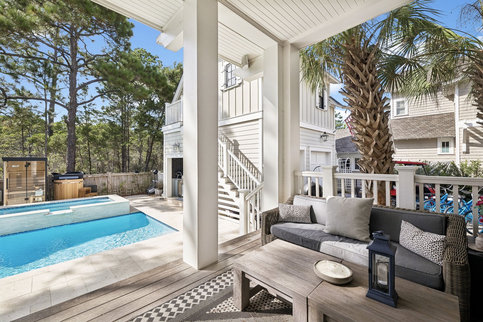 Relax under the covered patio with comfortable seating overlooking your private pool, hot tub, and lush surroundings—perfect for outdoor living and entertaining.