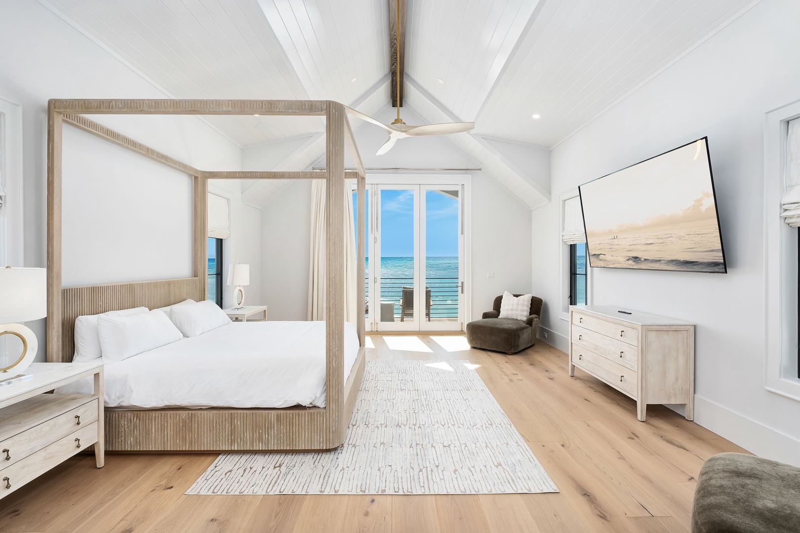 Wake up to stunning ocean views in this serene bedroom, where vaulted ceilings and luxurious four-poster bed create your perfect coastal retreat.
