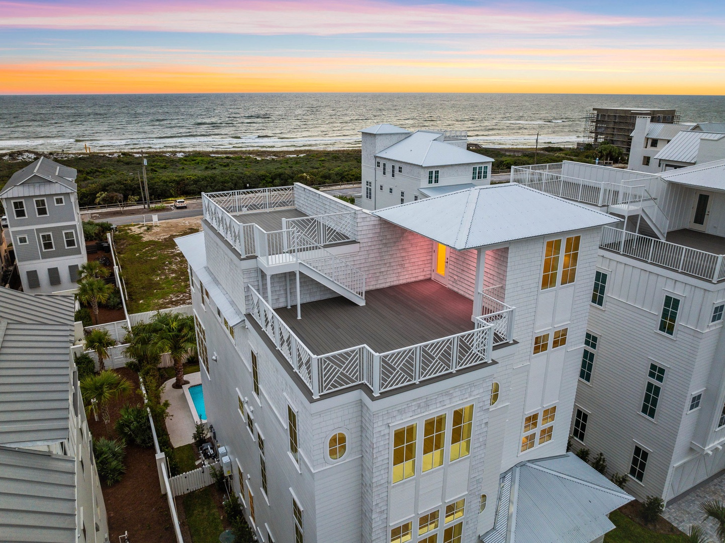 Stunning sunset colors paint the sky over this beachfront property, showcasing the coastal architecture and nearby ocean access.