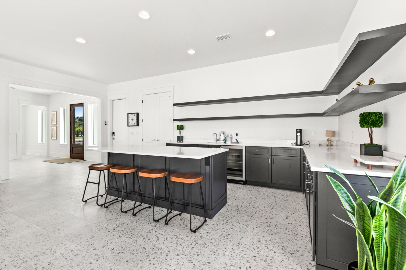 Gather around this sleek kitchen island with modern bar seating, where stylish dark cabinetry and bright white countertops create your perfect space for morning coffee or meal prep.