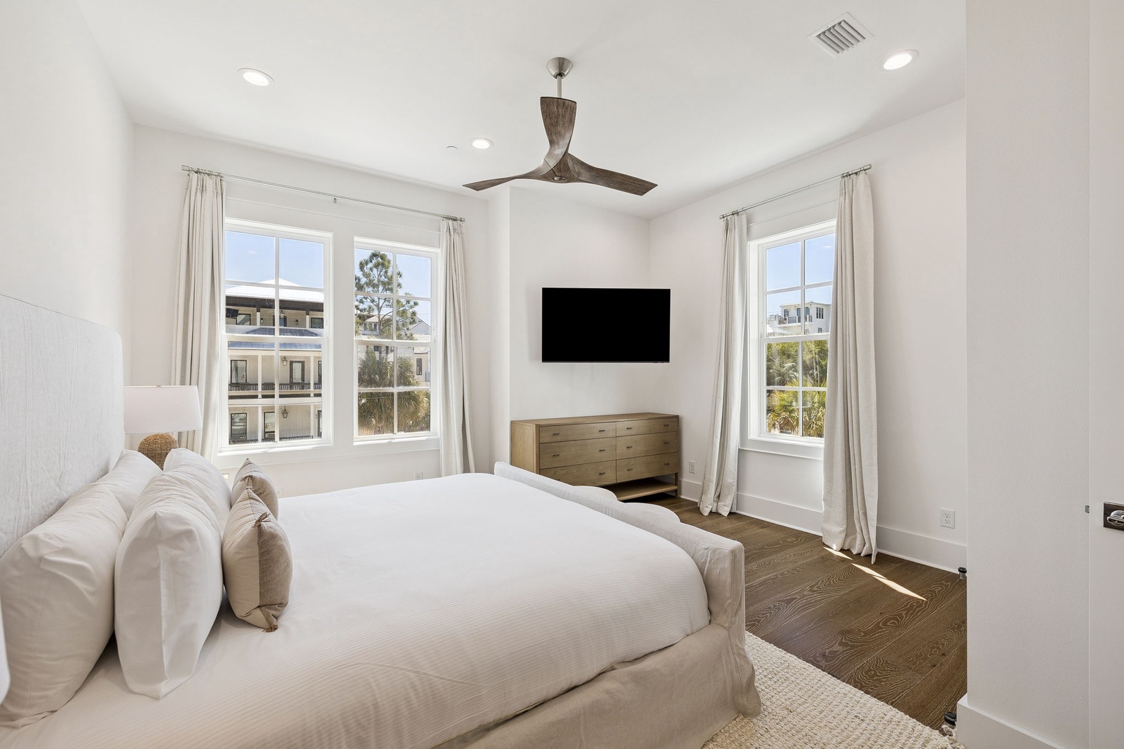 Unwind in your serene bedroom sanctuary with crisp linens, gentle breezes from the ceiling fan, and natural light streaming through dual windows.