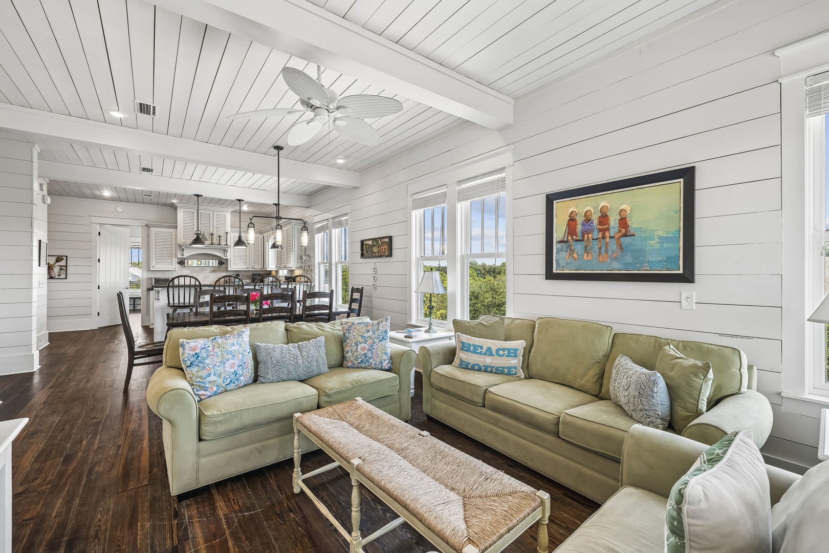 Settle into your bright, open-concept living space where coastal comfort meets breezy elegance. Natural light pours through French doors, vaulted ceilings soar above, and plush seating invites you to kick back after a day of exploring.