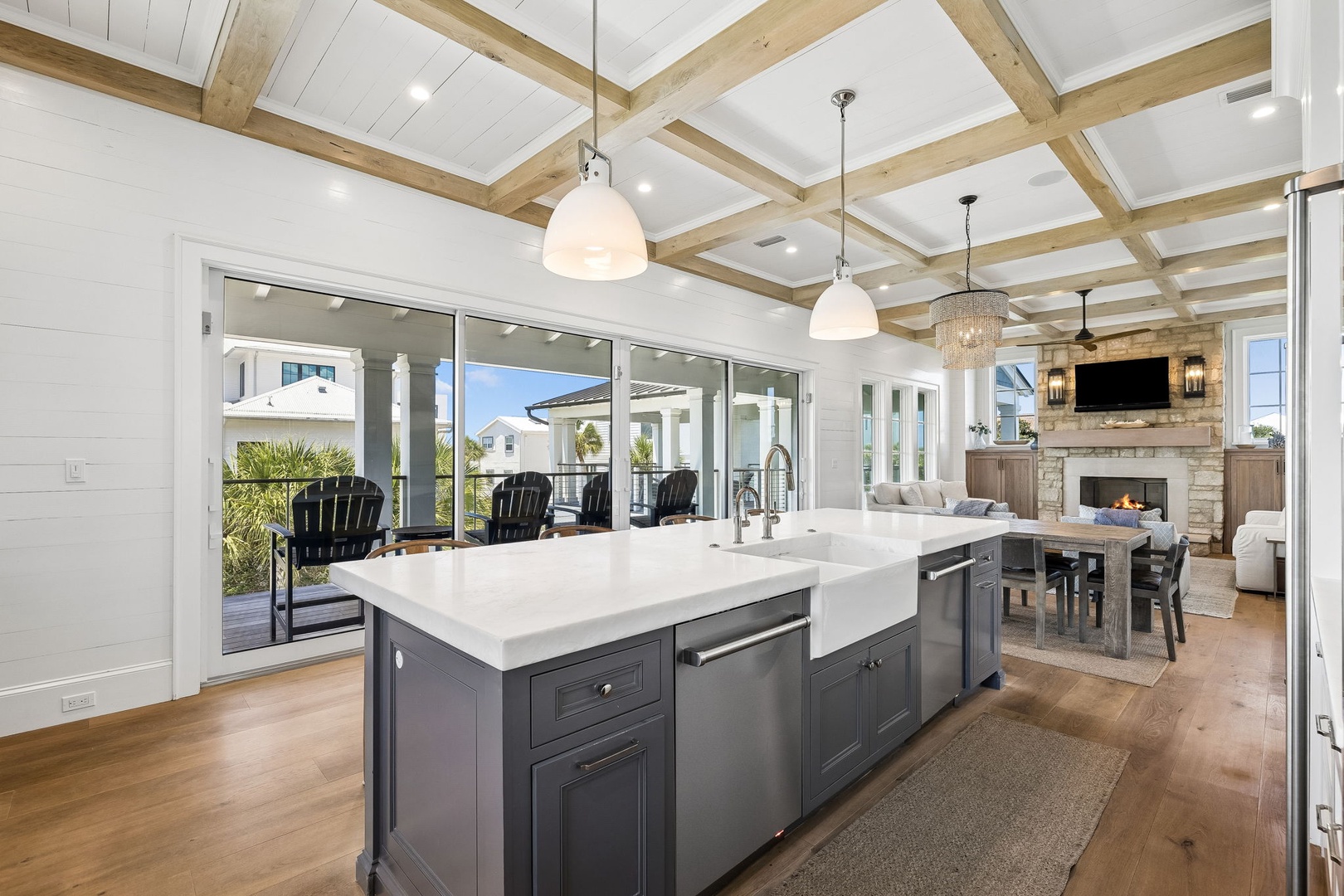 Step into this sun-drenched, open-concept living space where coastal elegance meets comfort. Vaulted ceilings with exposed beams frame your view to the outdoors, while the chef's kitchen invites you to gather, cook, and unwind by the fireplace.