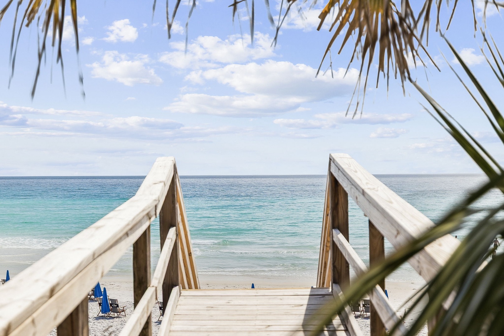 Wooden boardwalk leads directly to pristine beach with turquoise waters and soft white sand.