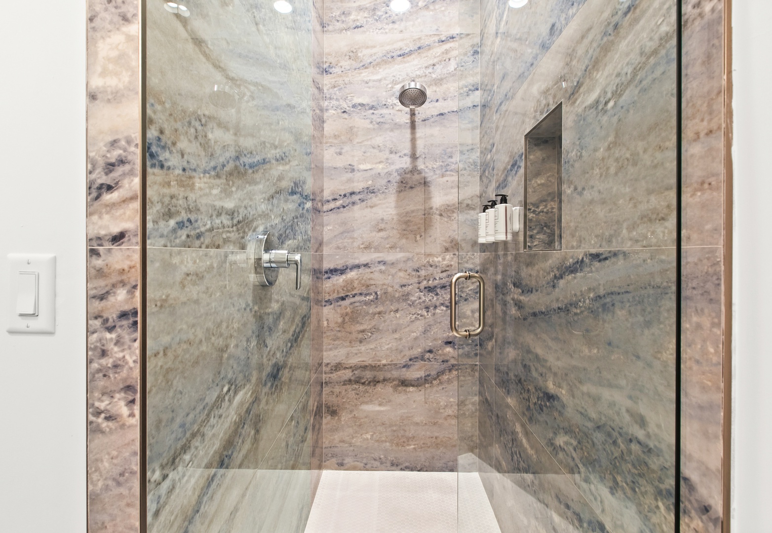 Step into your beautifully designed walk-in shower, where stunning marble-like stone wraps around you in soft waves of blue and beige. The rainfall showerhead and built-in niche add both luxury and convenience to your daily routine.