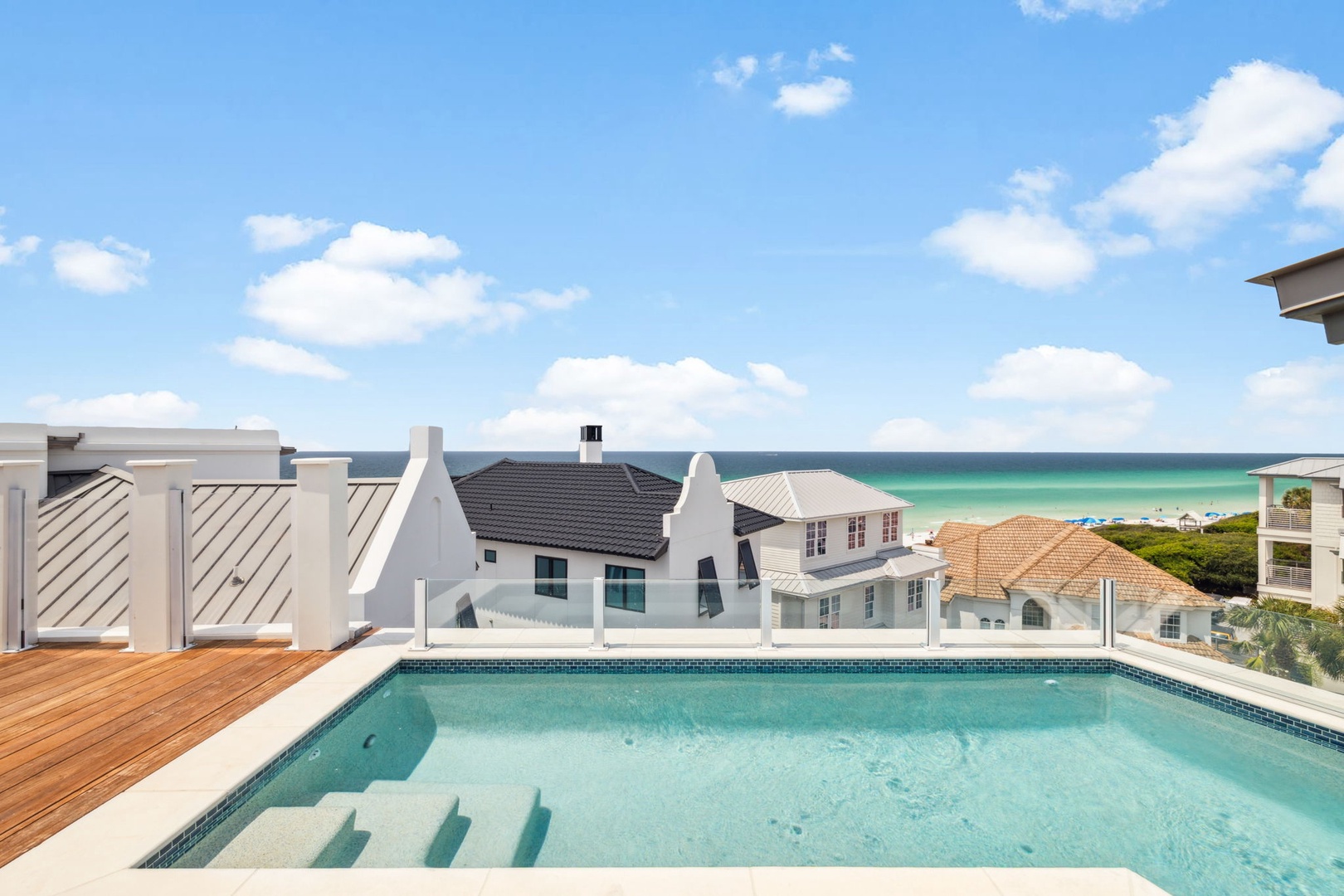 A rooftop terrace with a private pool offering panoramic ocean views. The wooden deck and pristine pool create the perfect coastal retreat for relaxation and sunbathing.