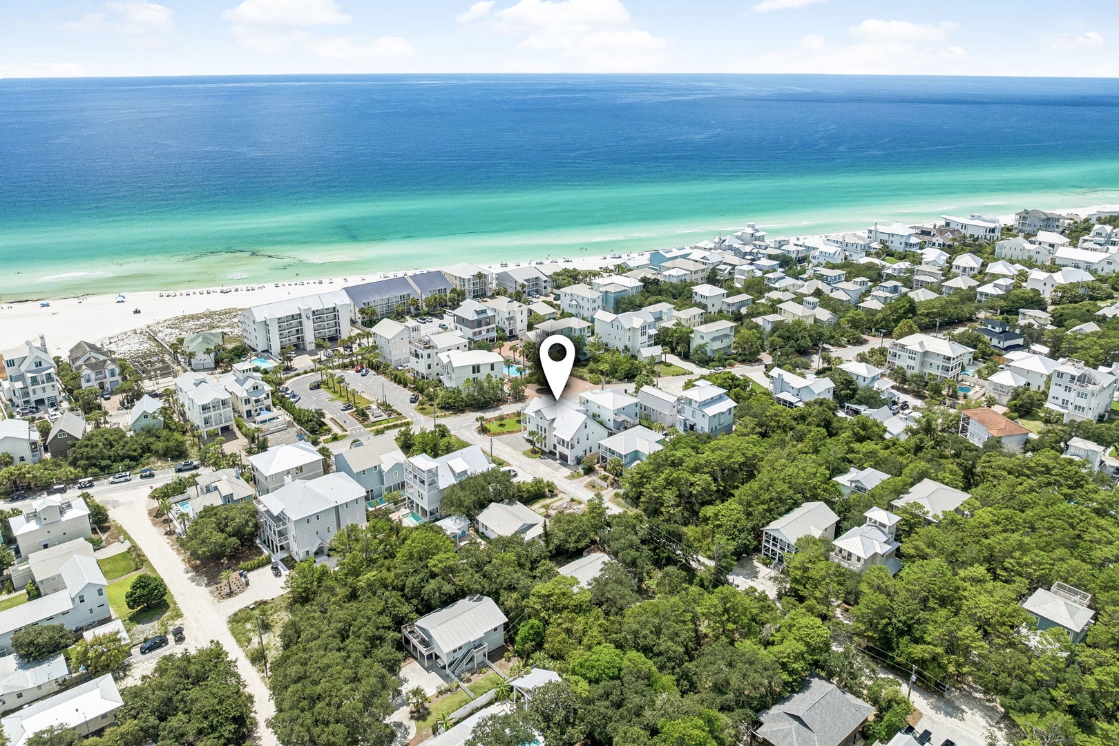 Aerial view of a coastal neighborhood nestled among lush greenery, moments from pristine white sand beaches and emerald Gulf waters.