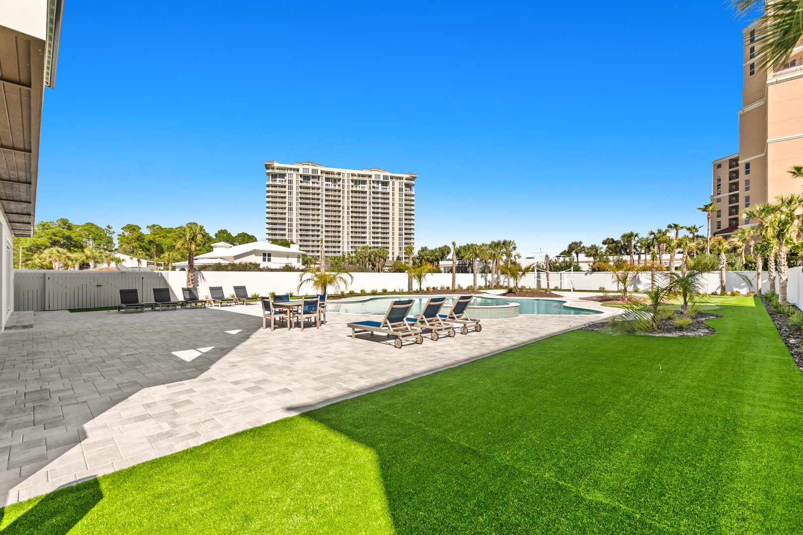 A spacious poolside oasis set in a private courtyard, framed by palm trees and abundant sunshine under clear blue skies—perfect for an entire day of outdoor living.