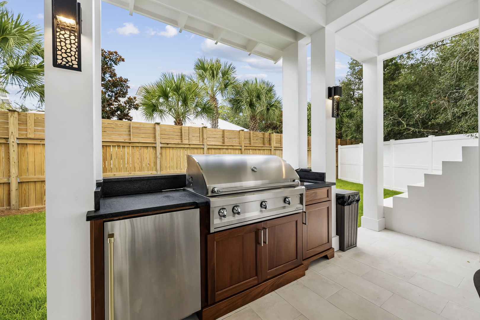 Your own covered outdoor kitchen awaits, complete with a stainless steel grill and ample counter space—perfect for grilling under swaying palms in your private backyard retreat.