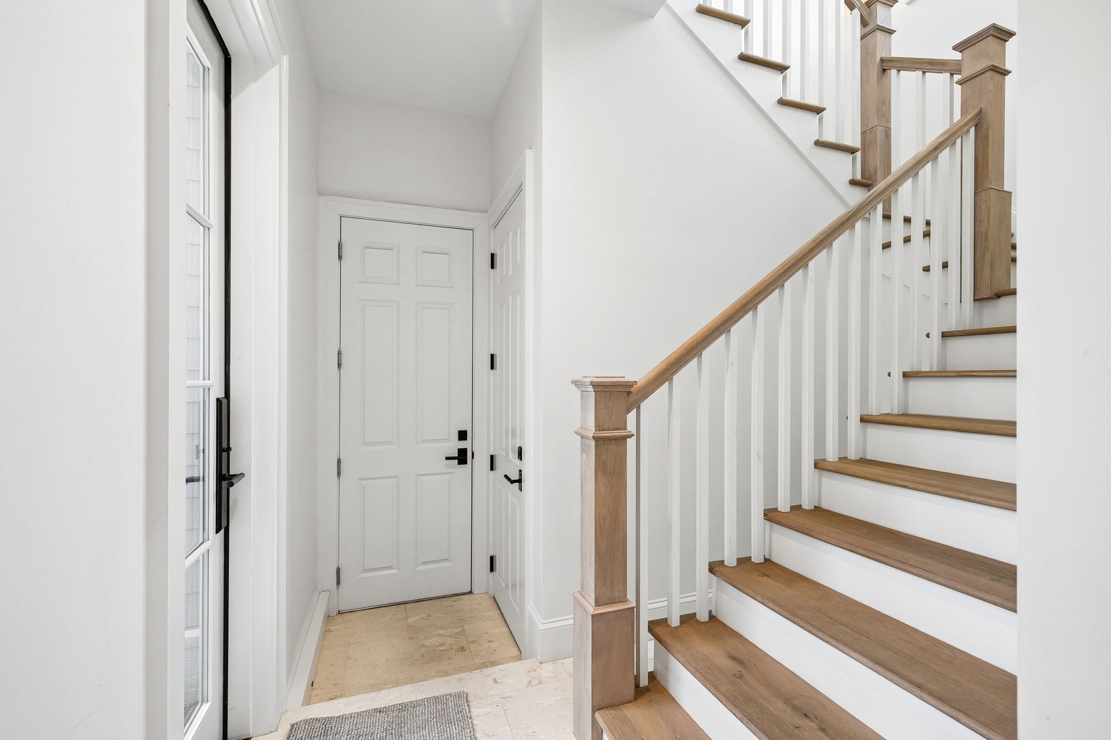 Step inside to find a bright, welcoming entryway with elegant wood-and-white staircase detailing that sets a refined tone for your entire stay.