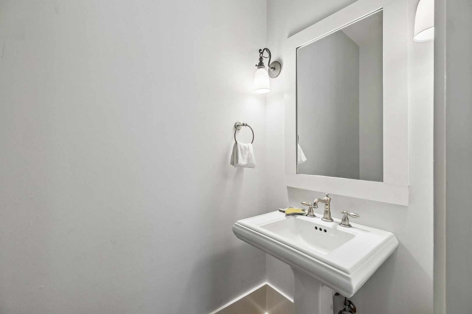 Freshen up in your private bathroom, featuring a classic pedestal sink and bright sconce lighting that makes every morning feel effortless.