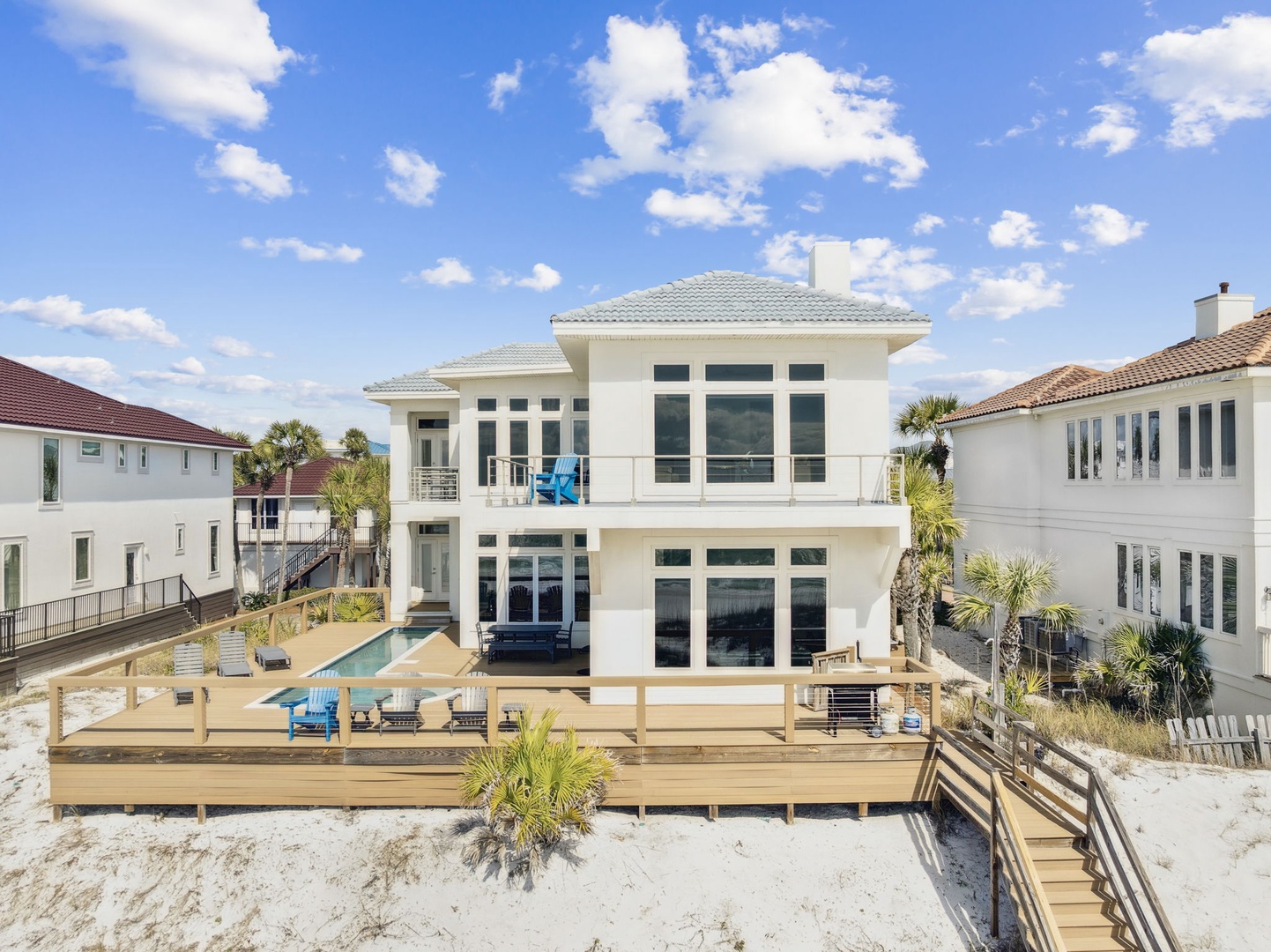 Modern beachfront home with expansive deck, private pool, and direct beach access in coastal neighborhood.