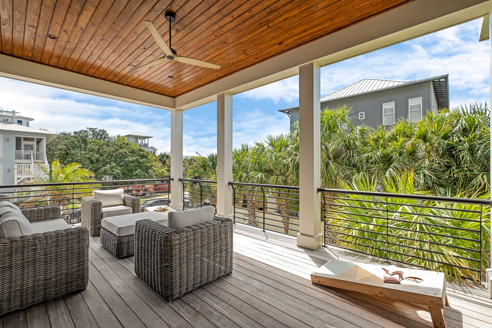 Your private covered deck offers plush seating where you'll unwind beneath warm wood ceilings, surrounded by lush tropical palms and peaceful neighborhood views.