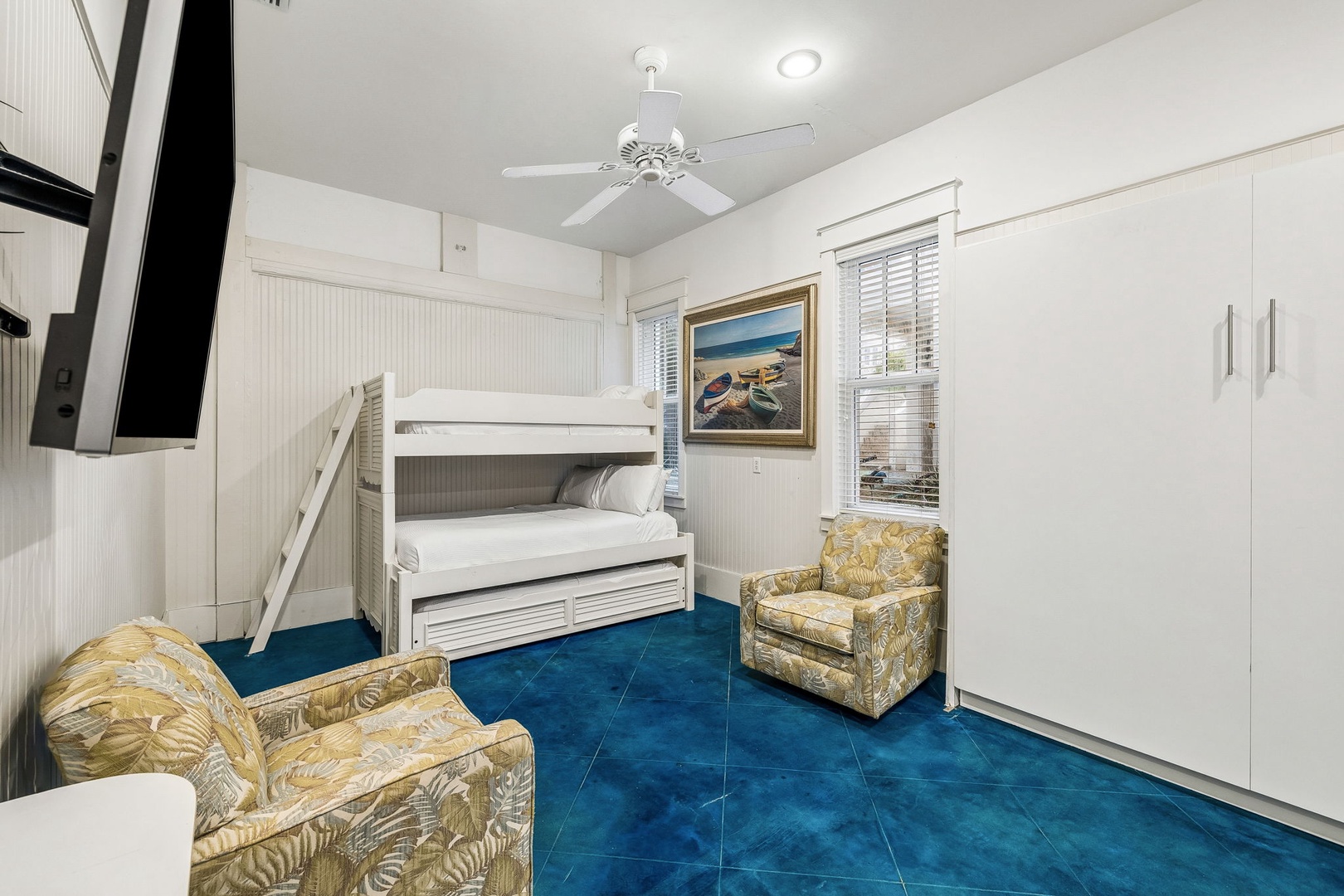 Bright, coastal-themed bedroom where the kids can unwind after a day of adventure. The bunk beds and vibrant blue flooring create a cozy, playful retreat for your family.