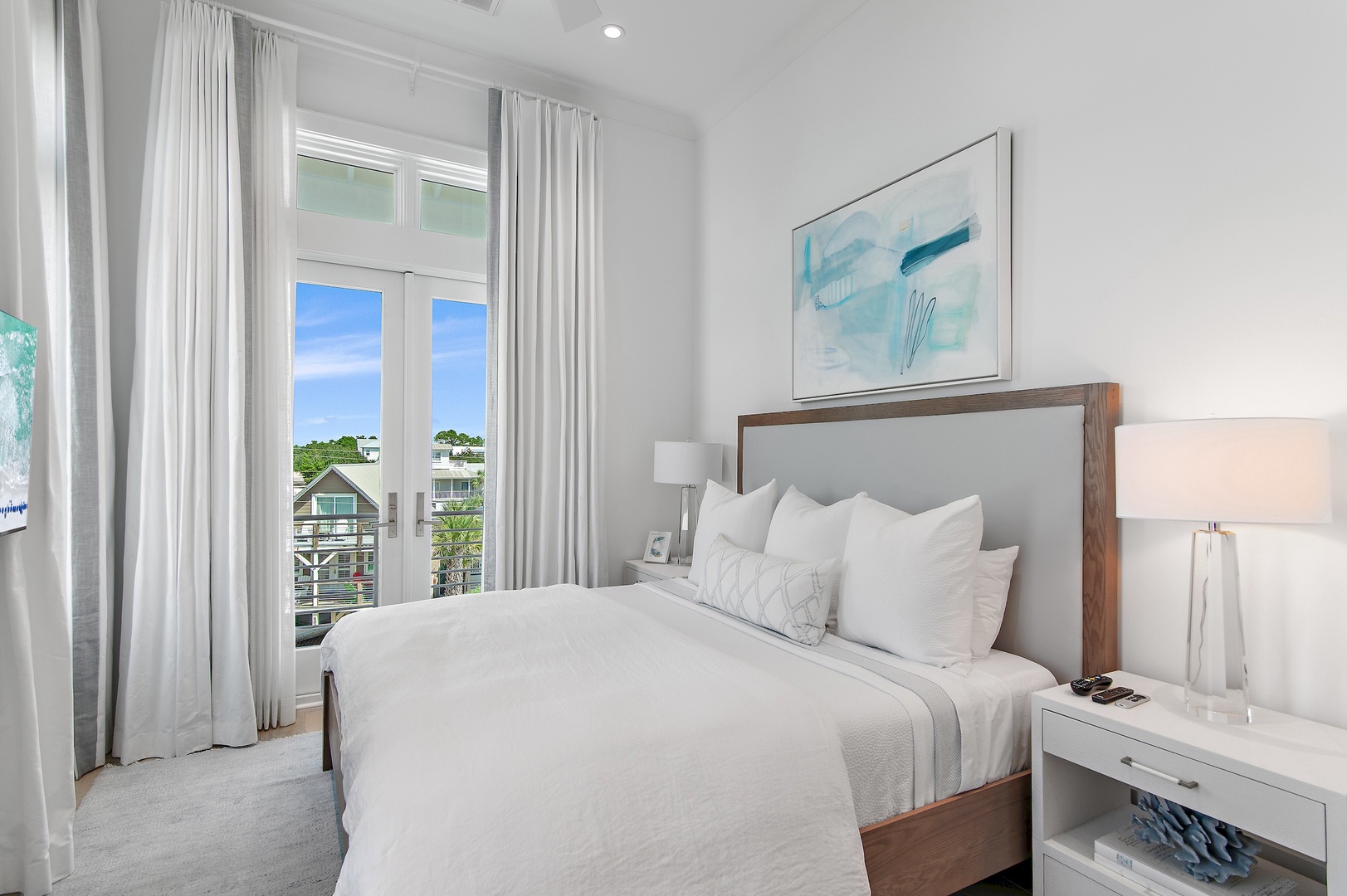 Sink into crisp linens in this serene bedroom where soft natural light and calming coastal artwork create your perfect retreat. Step onto your private balcony and enjoy peaceful neighborhood views.