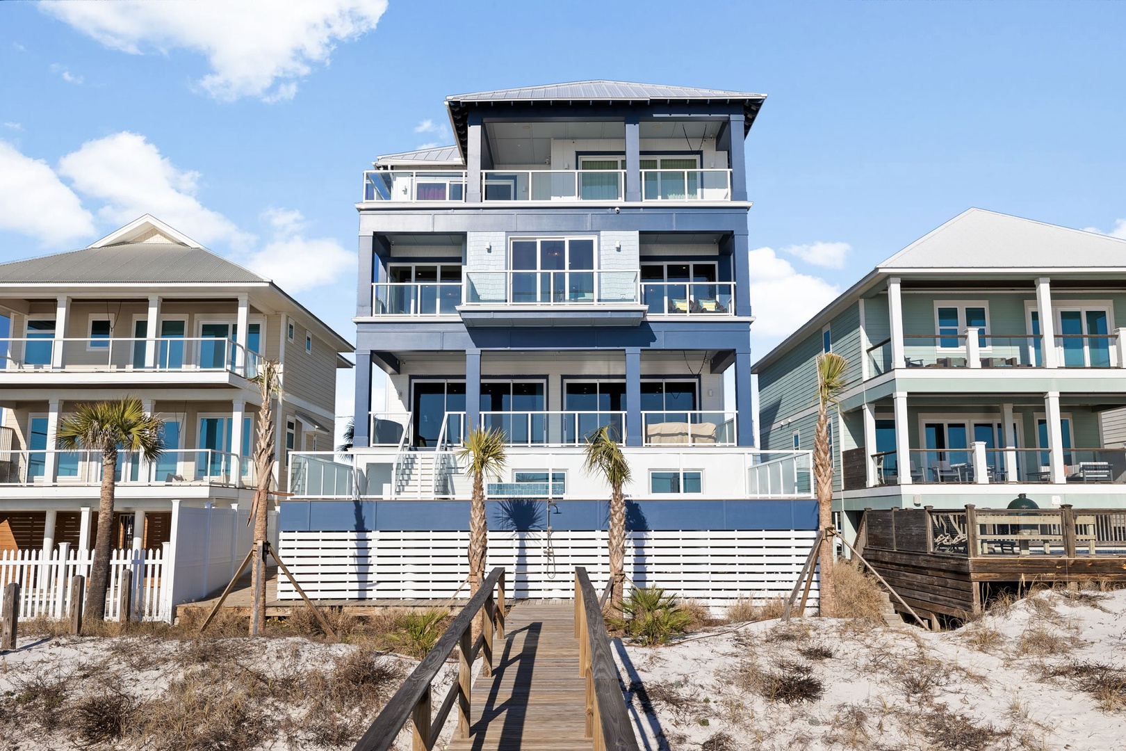 Modern beachfront property with multiple levels featuring expansive balconies and direct beach access via private walkway.