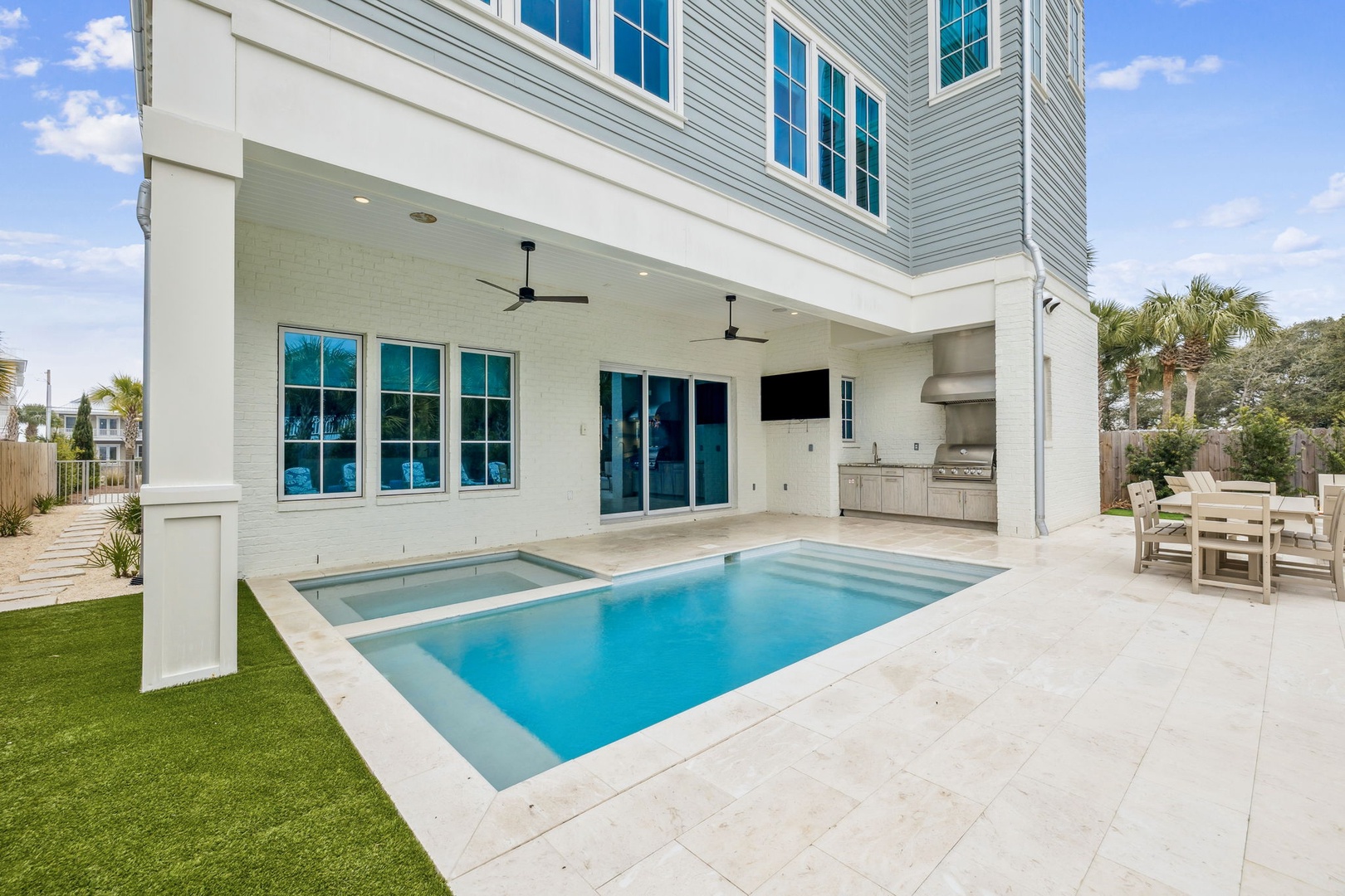 Modern beach house featuring a private pool with spa, covered outdoor kitchen, and lush tropical landscaping.
