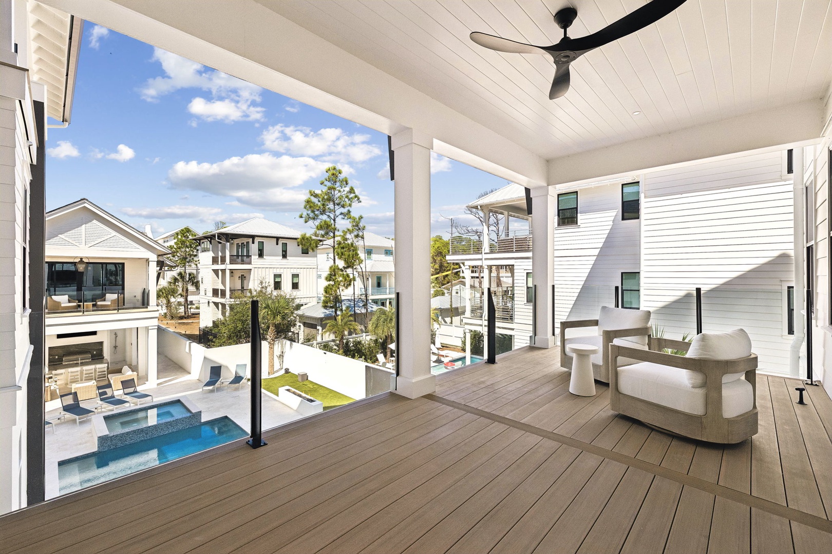 Step onto your private covered balcony, where crisp white ceilings and warm wood floors frame stunning pool and neighborhood views. Sink into plush seating and feel the gentle breeze from the overhead fan as you unwind in your peaceful retreat.