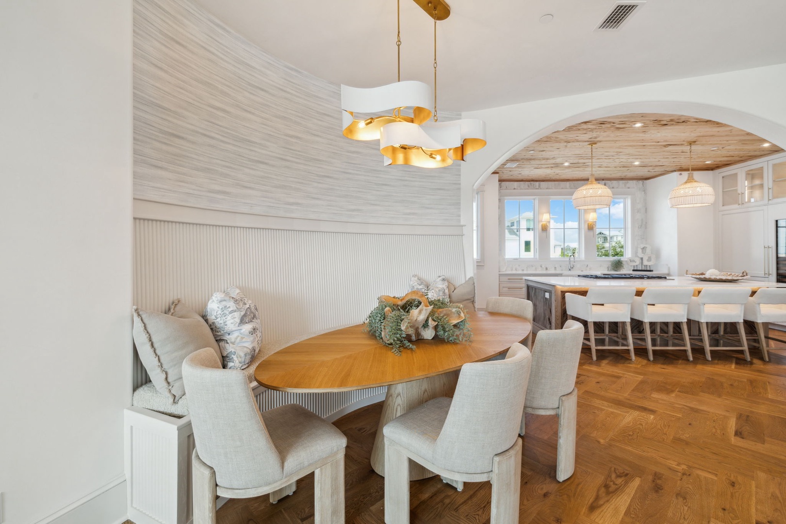 Gather around the elegant dining table with plush seating and natural light streaming through, while the open-concept kitchen invites culinary adventures under warm pendant lighting and rustic wood accents.