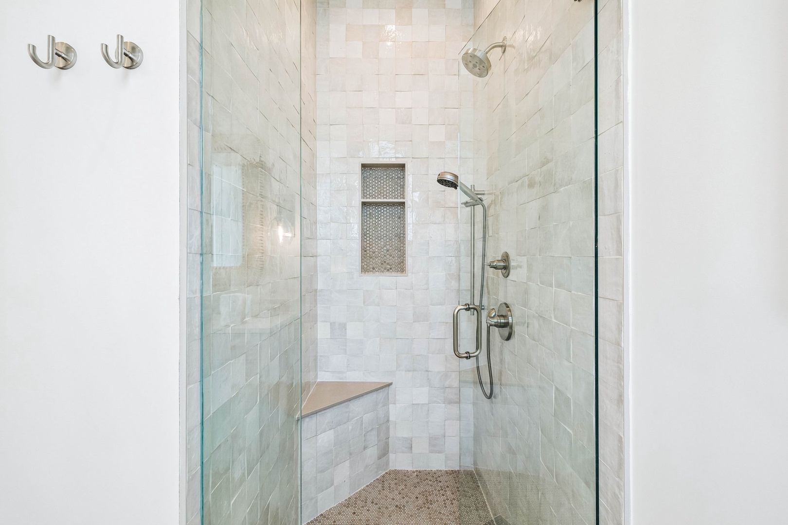 Step into your private spa-like sanctuary with a stunning walk-in shower finished in luxurious marble tile. A handheld spray and built-in seat invite you to relax and unwind after a day of exploring.