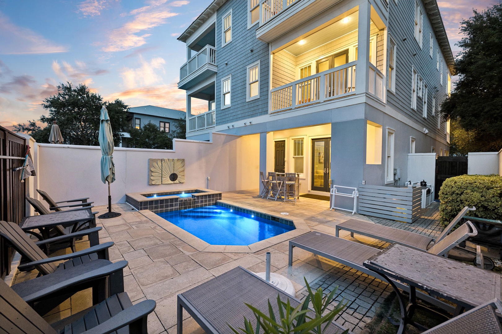 Stunning private pool area framed by dramatic sunset skies, where coastal-style architecture and modern outdoor lounging create your perfect retreat.