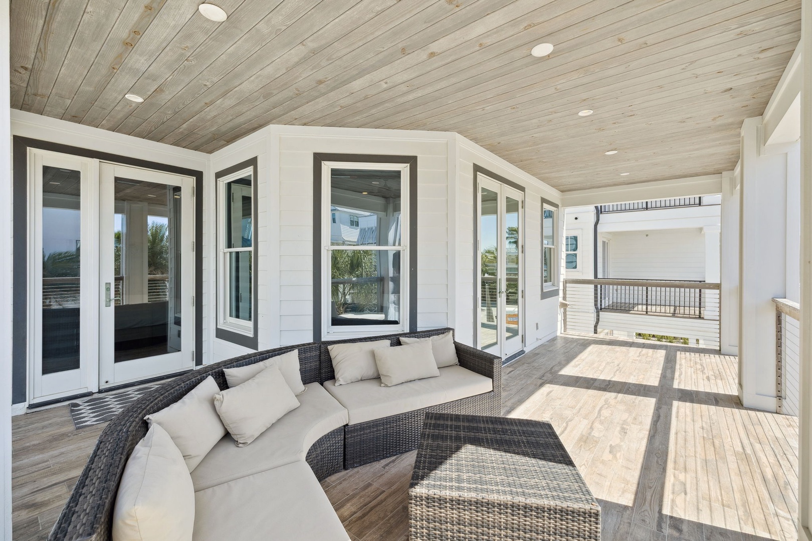 Unwind on your private covered terrace with plush seating, perfect for morning coffee or evening conversations under the wood-paneled ceiling.