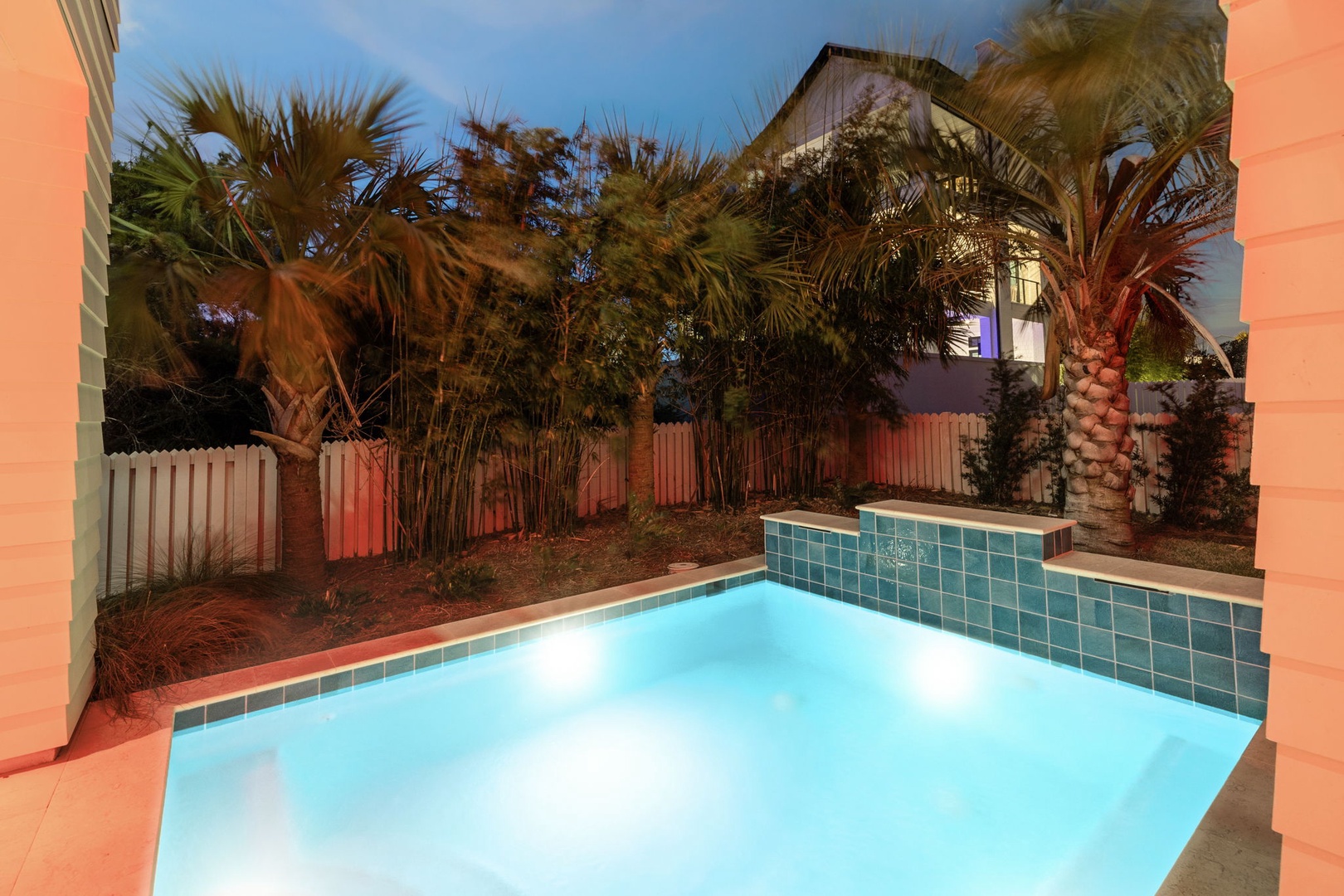 Your private pool oasis awaits, illuminated for magical evening swims among tropical palms and lush landscaping.