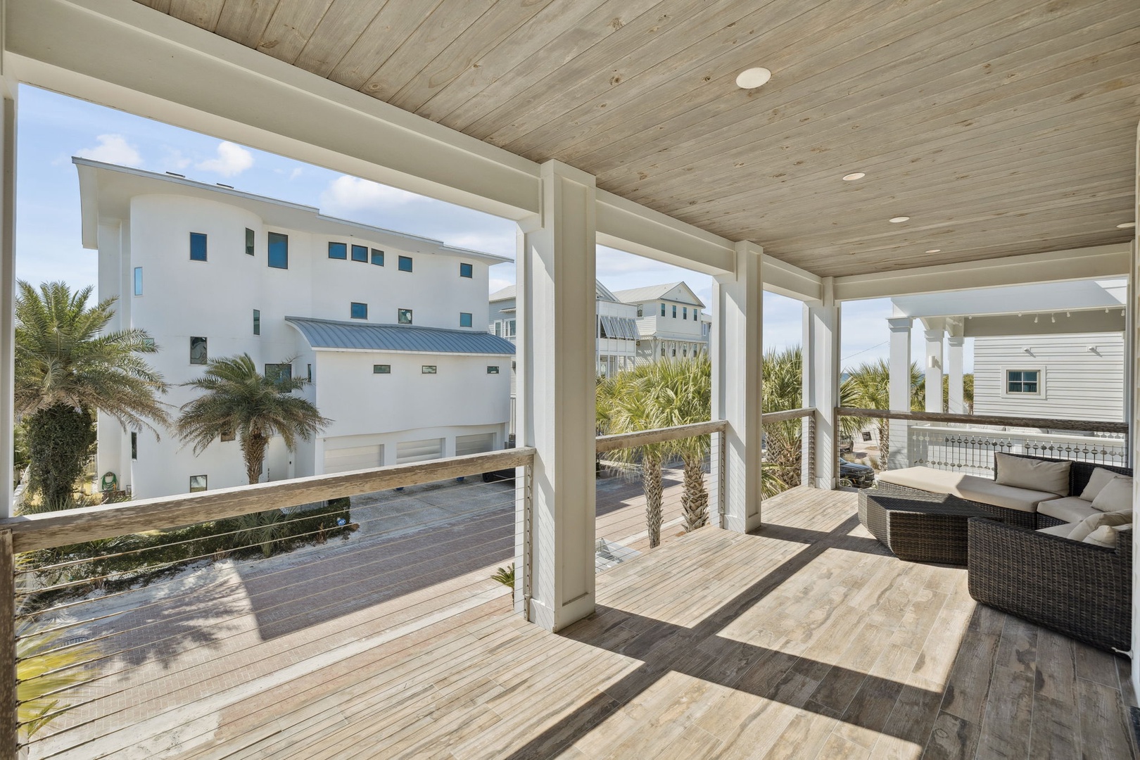 Relax on your private covered balcony with comfortable seating and stunning neighborhood views of coastal architecture and palm trees.