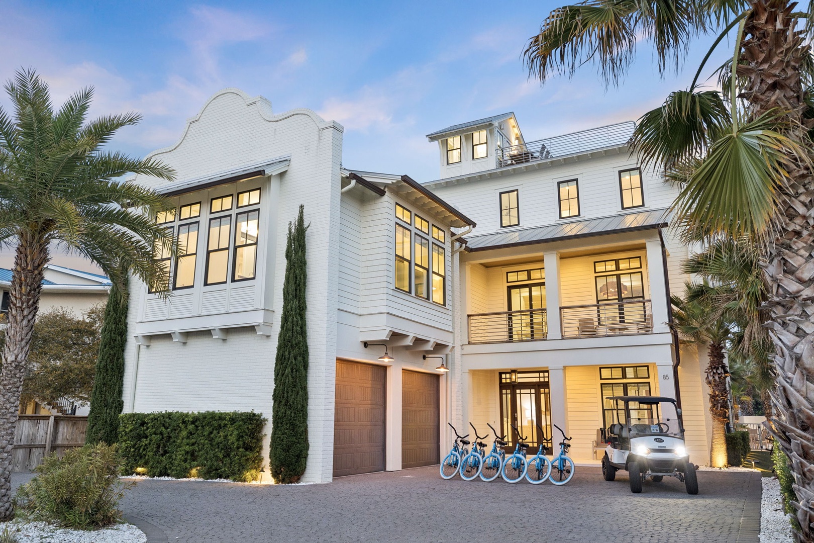 Modern luxury property featuring white architecture, palm trees, and complimentary bicycles for exploring the coastal area.