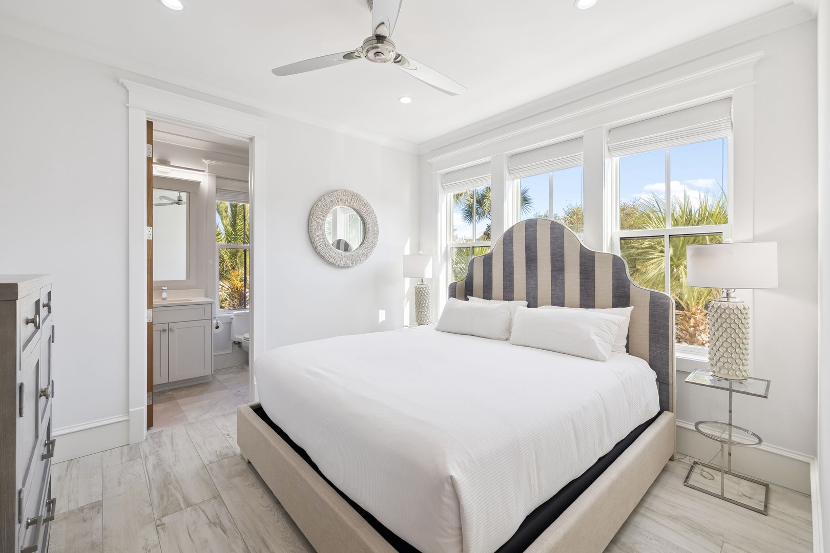 Sink into crisp linens in your bright coastal bedroom, where tropical palms sway just beyond your windows and gentle breezes keep you cool.