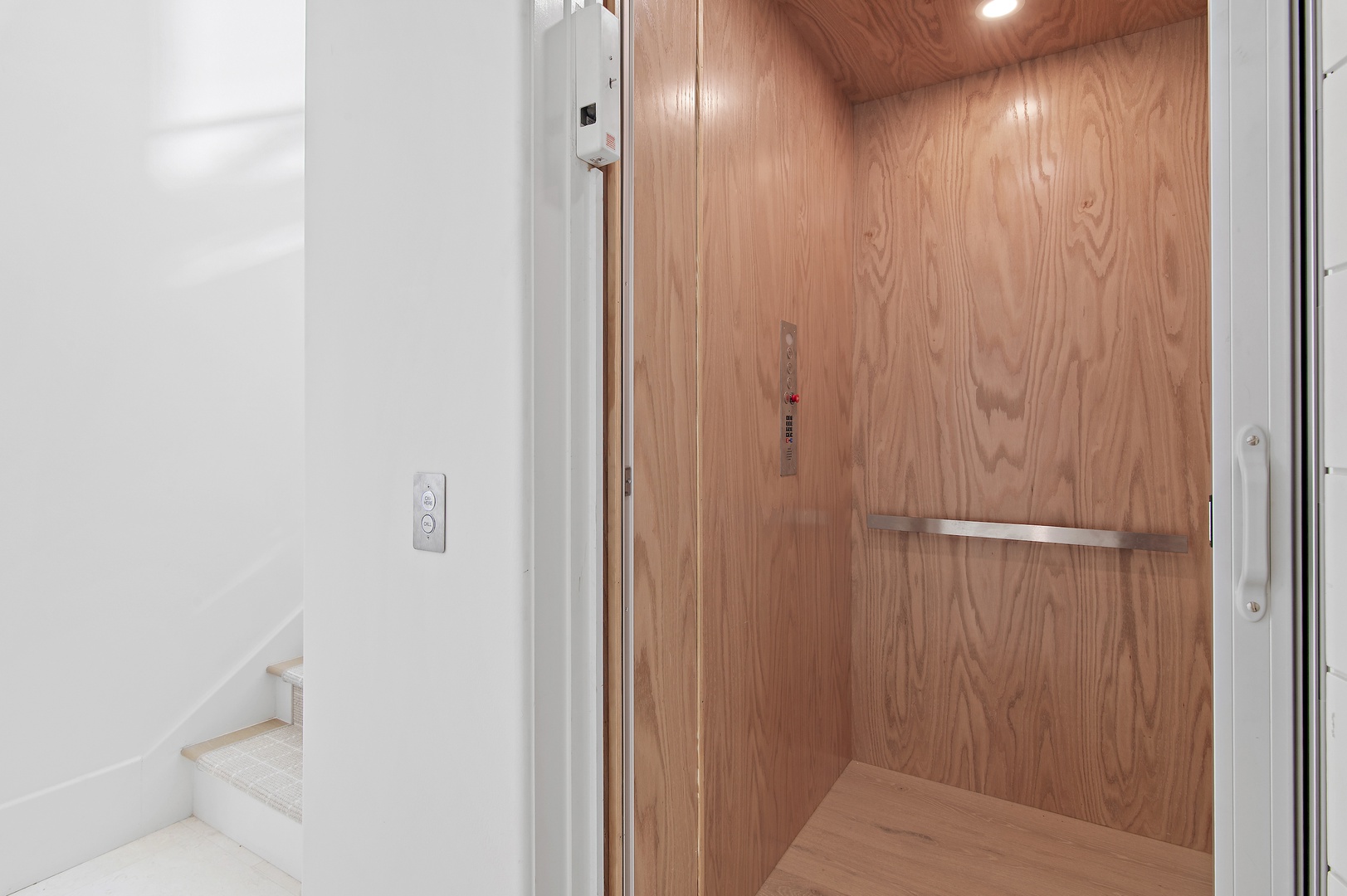An elevator with warm wood paneling and metal handrail provides easy access throughout your stay, ensuring convenience for all.