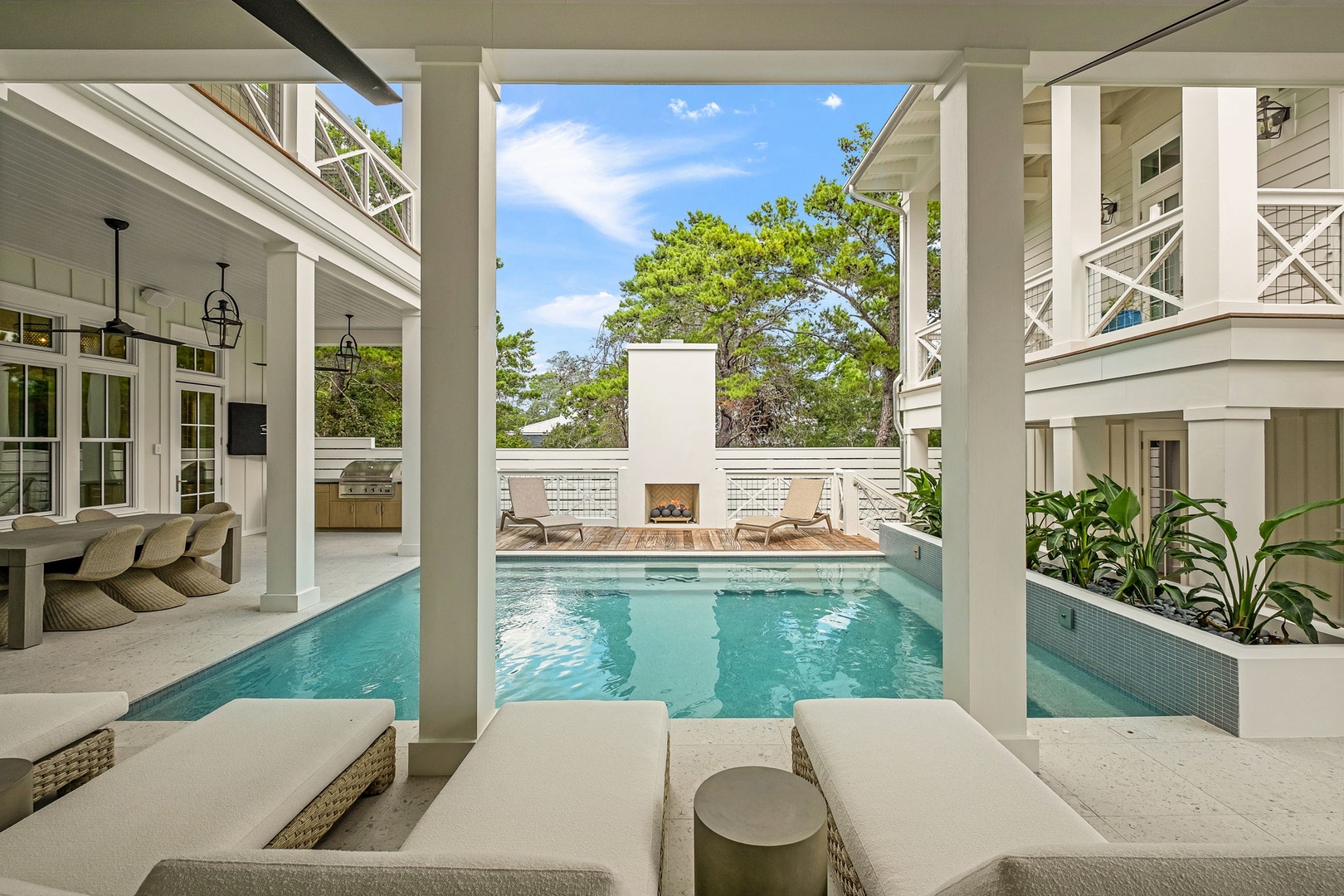 Your private courtyard pool awaits, framed by elegant columns and lush greenery, with inviting loungers and a cozy fireplace ready to make your getaway unforgettable.
