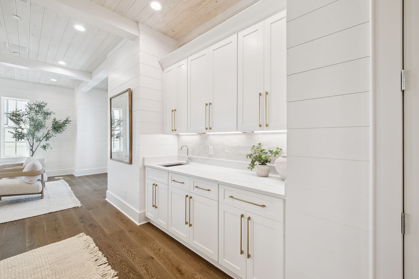 You'll love preparing morning coffee in this pristine white kitchen, featuring elegant brass hardware and marble countertops that catch the natural light beautifully.