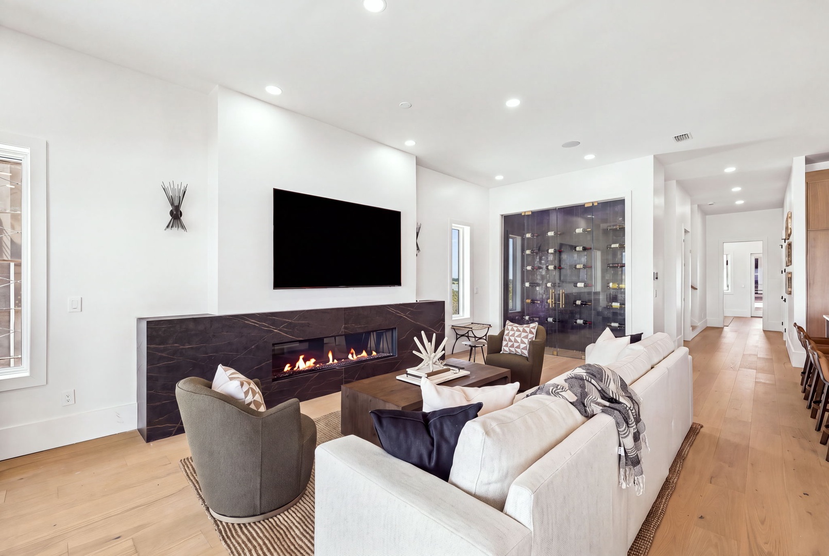 Settle into your bright, open living room where plush seating surrounds a sleek modern fireplace—perfect for cozy evenings or catching up with loved ones in effortless comfort.