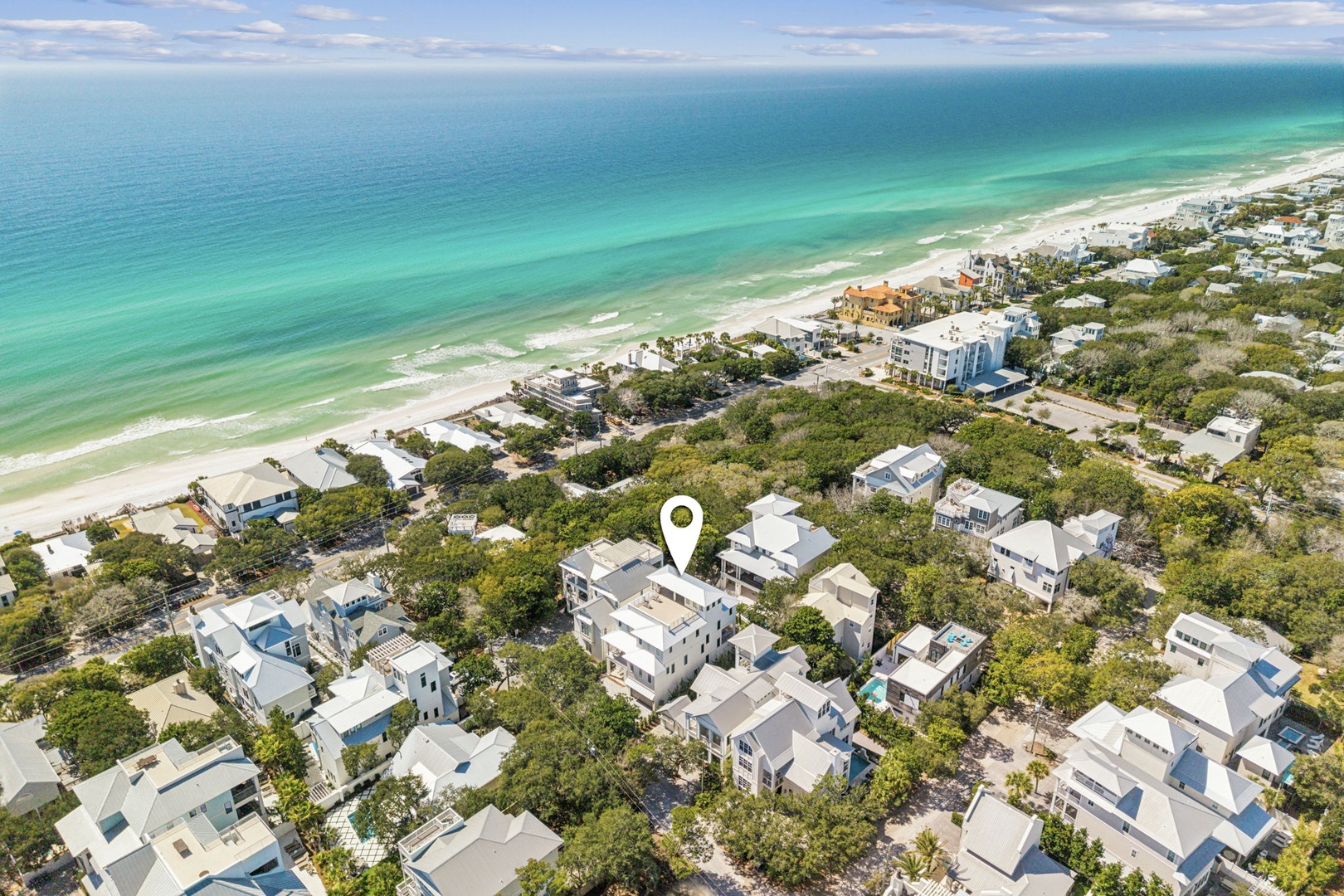 Aerial view showcasing the property's prime location among coastal homes, nestled between lush vegetation and pristine turquoise waters.