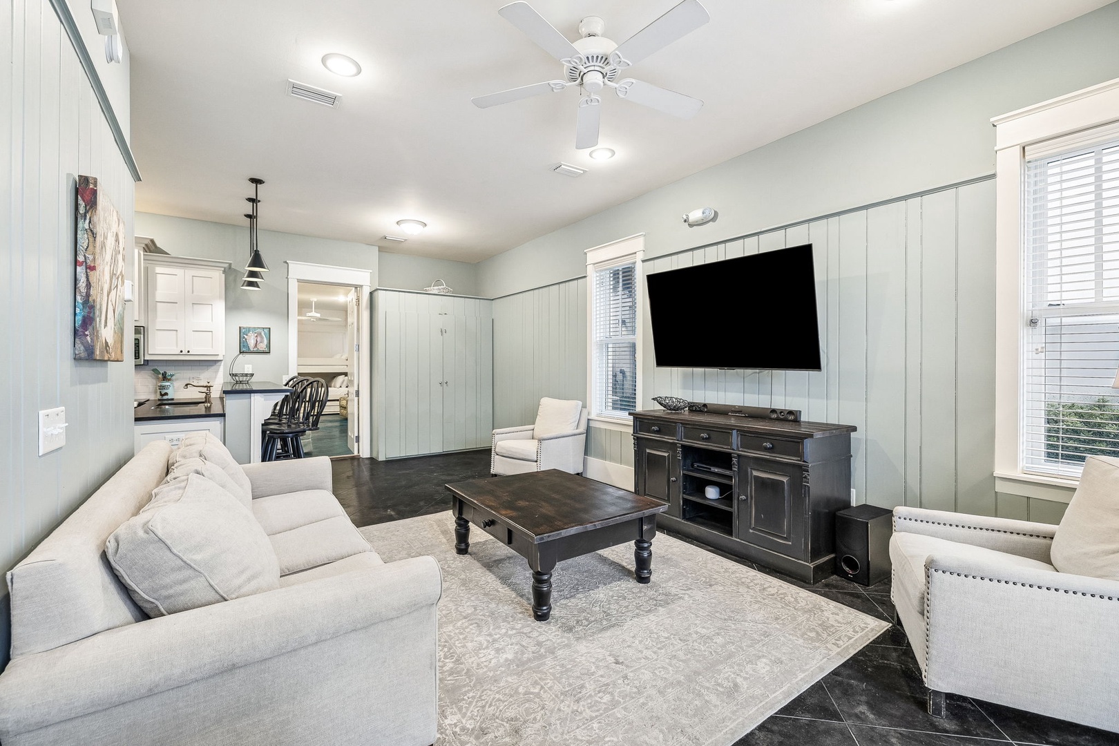 Unwind in your spacious living room, where coastal charm meets comfort. Sink into plush seating, enjoy the open flow to the kitchen, and let the ceiling fan keep you cool as you relax in this inviting retreat.